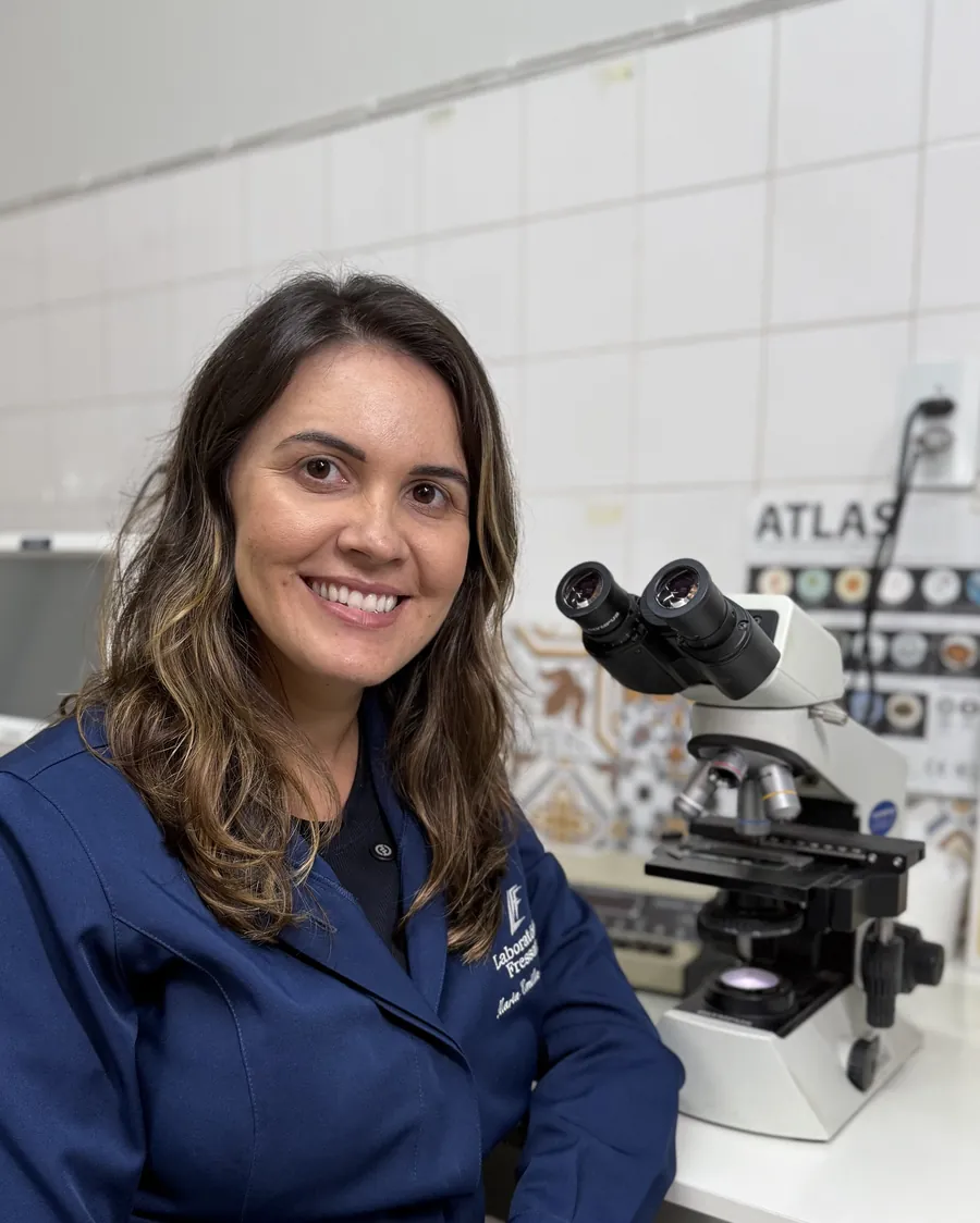 Biomédica do Laboratório Fressato ao lado do microscópio