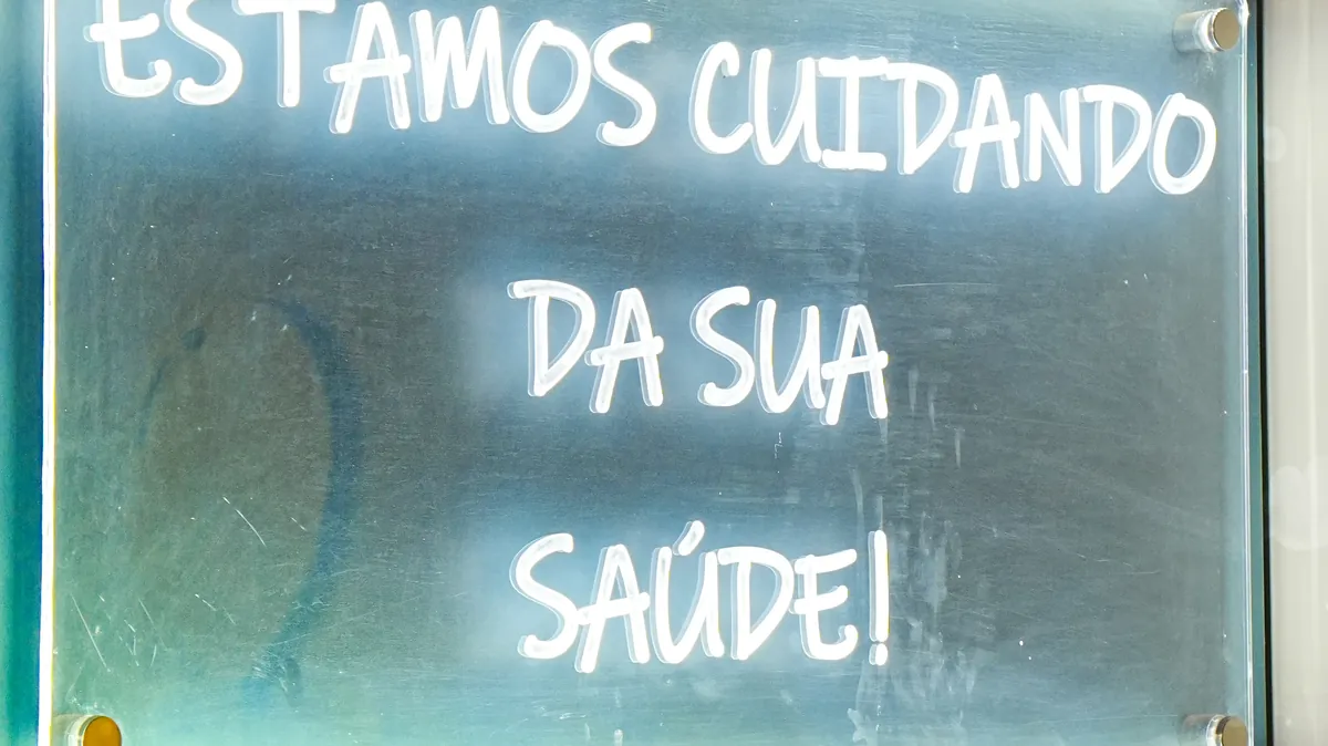 Letreiro em neon com a frase Estamos cuidando da sua saúde